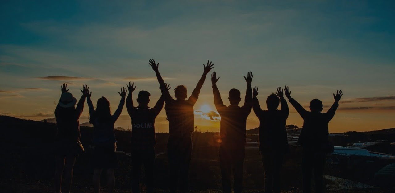 grupo de personas mirando el horizonte y levantando las manos